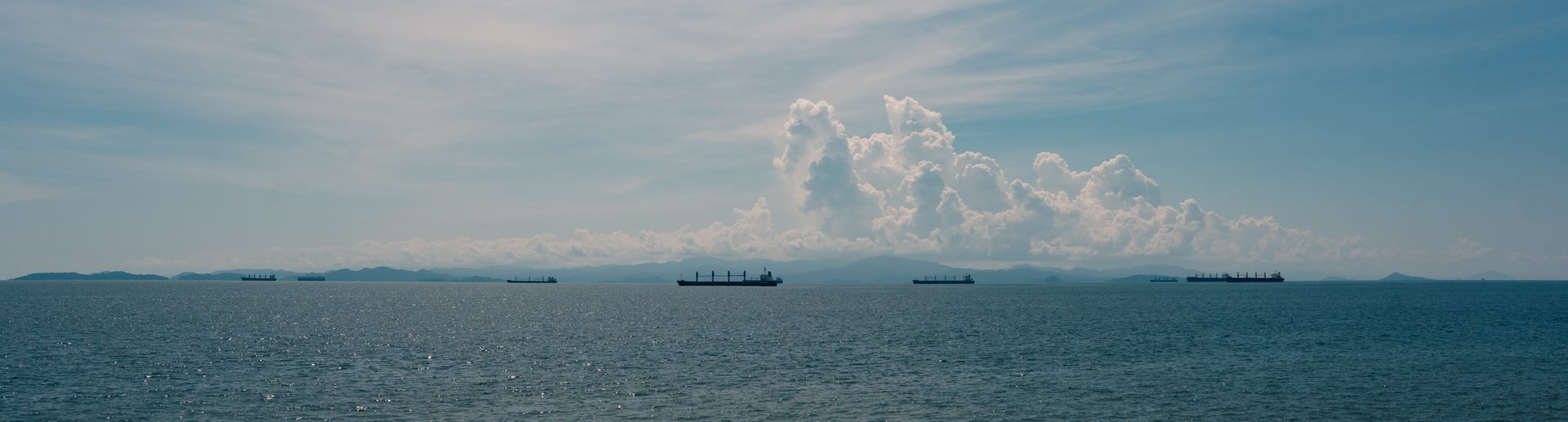 Frachtschiffe vor einer dramatischen Wolkenformation am Horizont